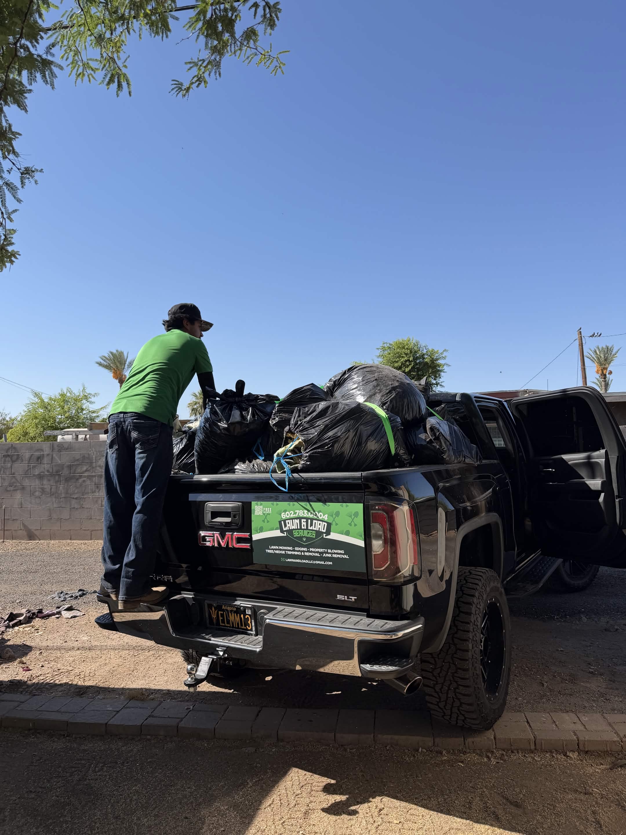 Lawn and Load worker securing a full junk-removal load in the company truck